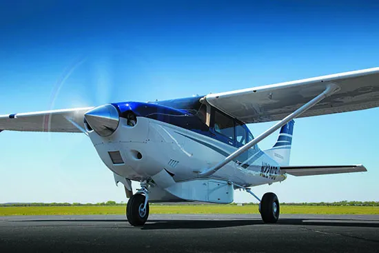 Cessna 206 blue with blue sky in a field.