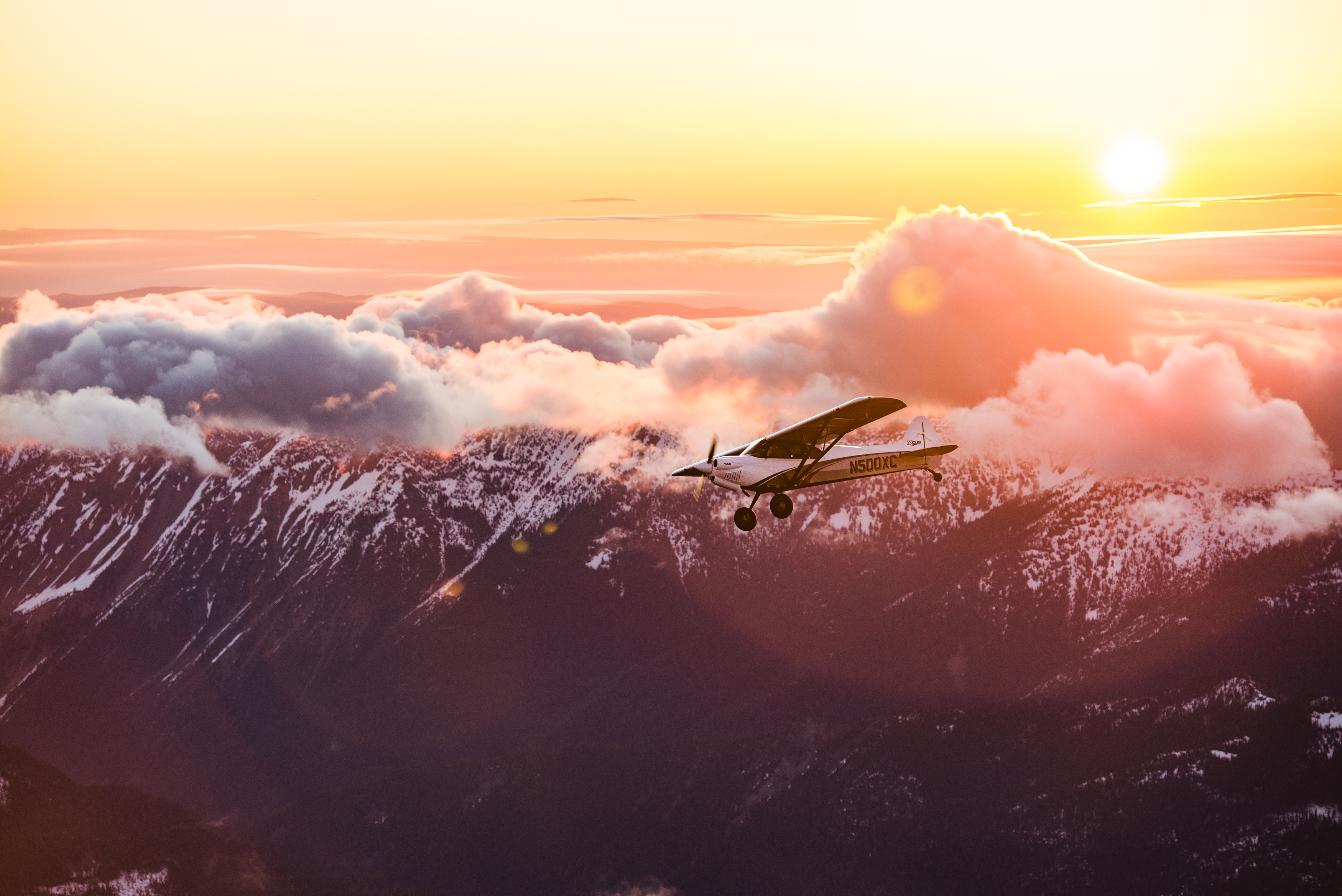 CubCrafters XCub in flight at sunset over snow-capped mountains — financed by FLYING Finance