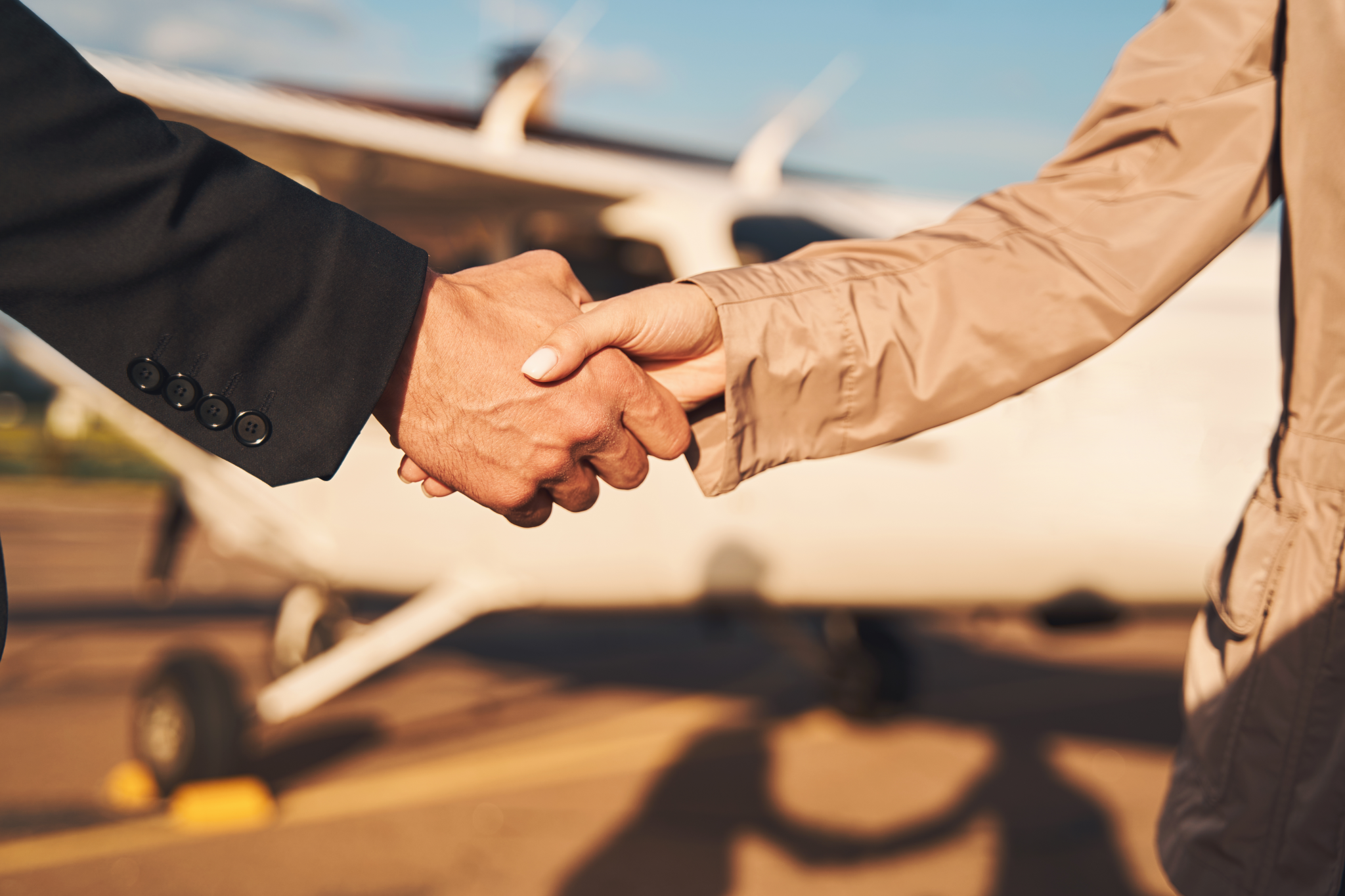 Pilot and buyer shaking hands in front of a Cessna single, sealing an aircraft purchase